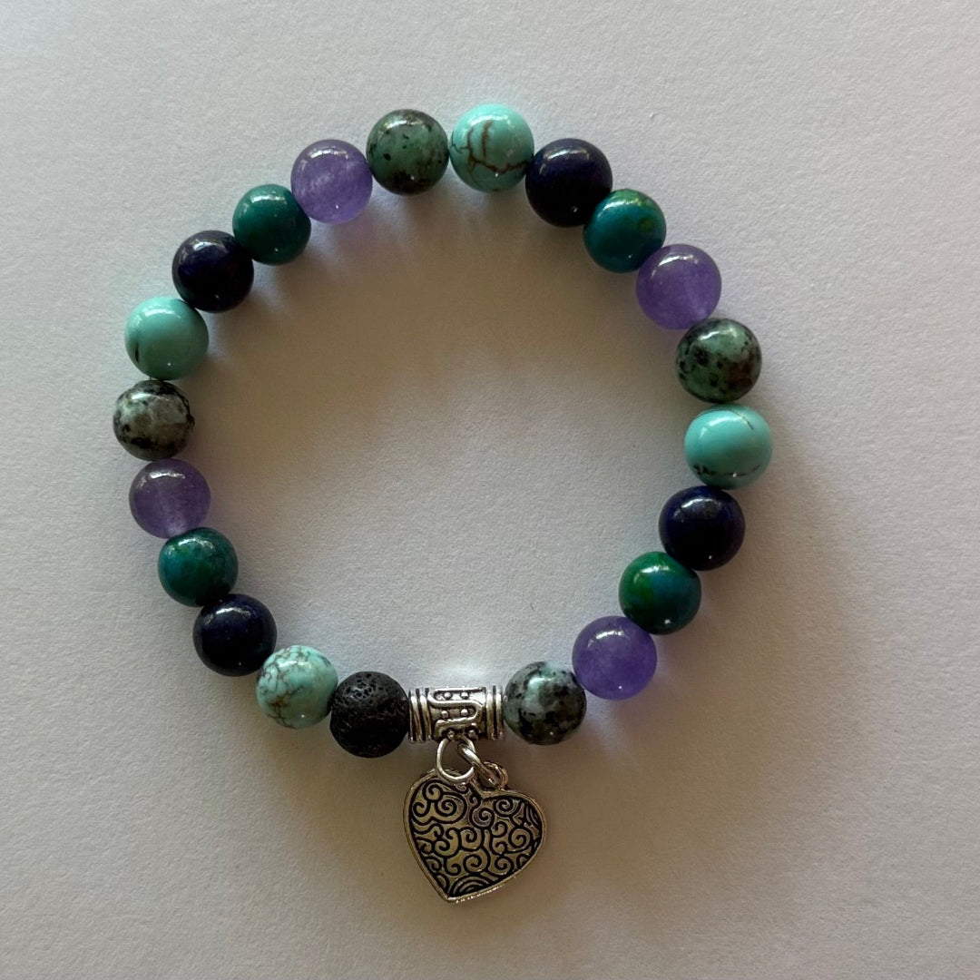 Beaded gemstone bracelet with a heart charm on a white background