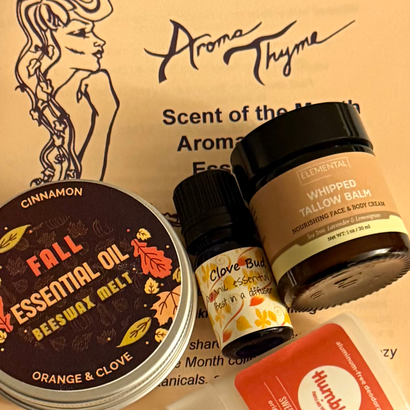 Collection of Aroma Thyme products including essential oil, beeswax melt, and cream on a branded background.